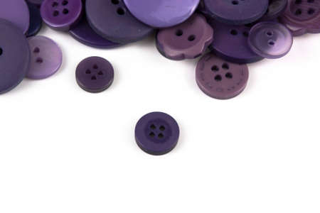 Close up of various purple button scattered on a white surface.の写真素材