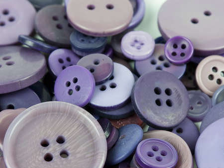 Close up of various purple button scattered on a white surface.の写真素材