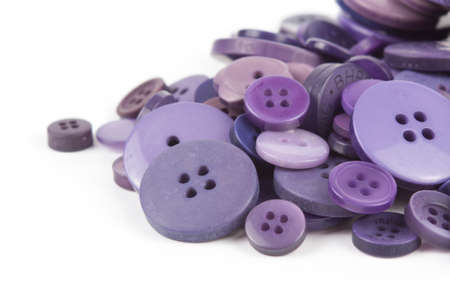 Close up of various purple button scattered on a white surface.の写真素材