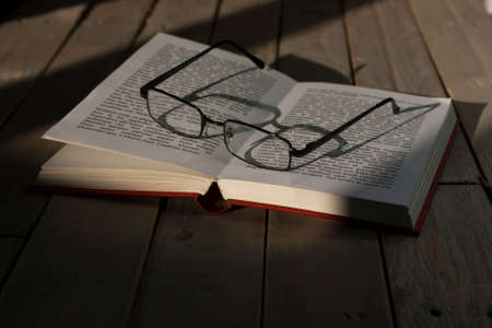 Glasses and books on an old wooden surfaceの写真素材