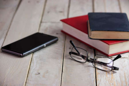 Glasses and books on an old wooden surfaceの写真素材