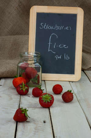 Fresh stawberries spilt on wooden table from jarの写真素材