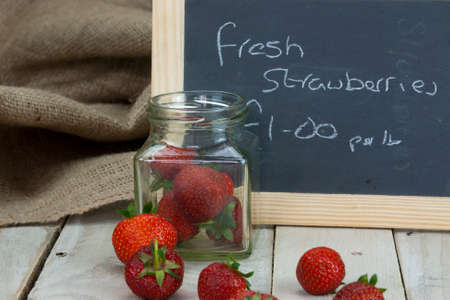 Fresh stawberries spilt on wooden table from jar