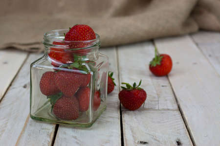 Fresh stawberries spilt on wooden table from jarの写真素材