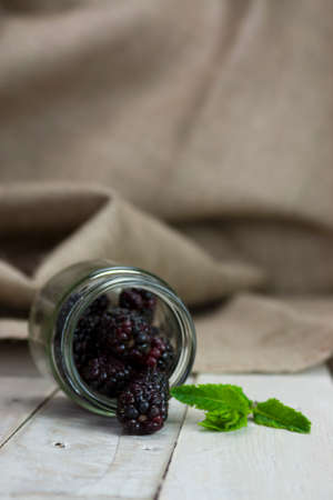 Fresh blackberries spilt on wooden table from jarの写真素材