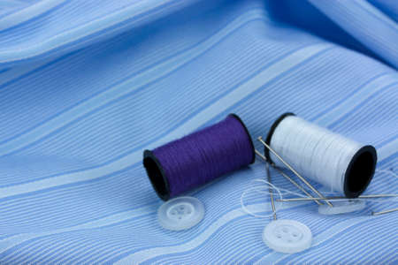 Needle cotton and thimble used for sewing left on a wooden surface