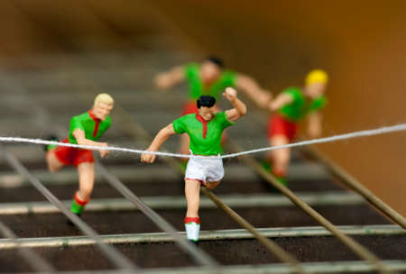 Miniature men in a race running down the arm of a guitar.の写真素材