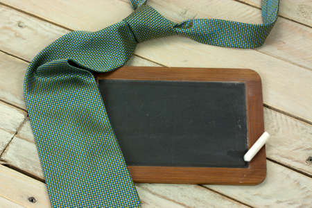Tie and small blackboard set against a wooden backgroundの写真素材