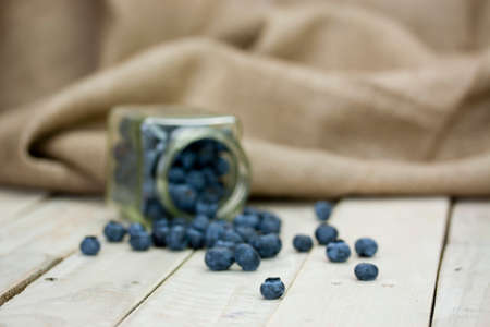 Blueberries spilt from a jar on a rustic surfaceの写真素材