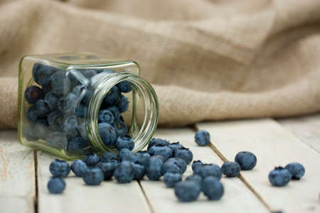 Blueberries spilt from a jar on a rustic surfaceの写真素材