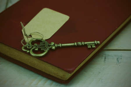 Close up of old vintage keys and book on a rustic background. Vintage filter applied.の写真素材