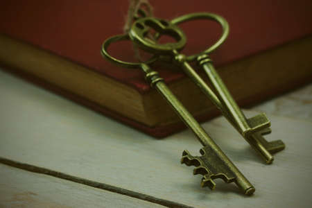 Close up of old vintage keys and book on a rustic background. Vintage filter applied.の写真素材
