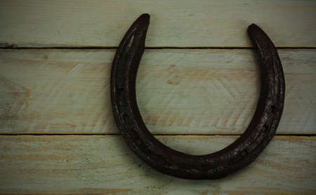 Metal horseshoe on a wooden background. Vintage filter applied.