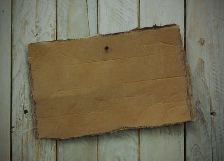 Distressed cardboard sign on a wooden background. Vintage filter applied.の写真素材