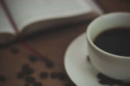 White coffee cup and saucer against a rustic background. Vintage filter applied.