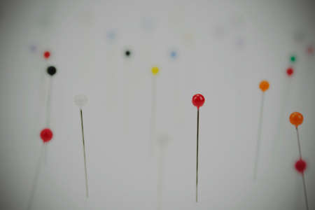 Close up of different coloured pins on a light background. Shallow depth of field. Vintage filter applied.の写真素材