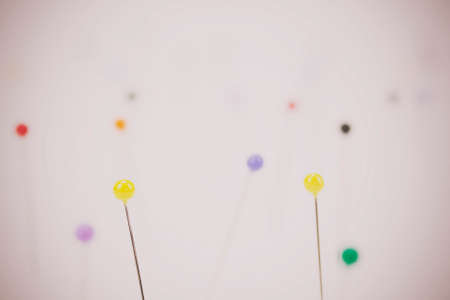 Close up of different coloured pins on a light background. Shallow depth of field. Retro filter applied.の写真素材