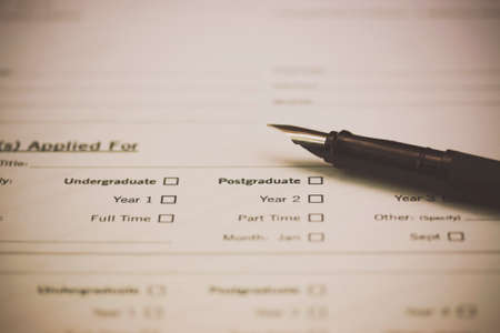 Close up of a fountain pen on a university application form. Retro filter applied.の写真素材