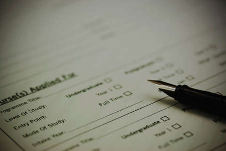 Close up of a fountain pen on a university application form. Vintage filter applied.の写真素材