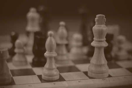 Wooden chess set with a game being played. Black and white filter applied.