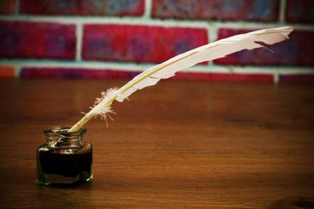 White feather quill pen with metal nib. Retro filter applied.