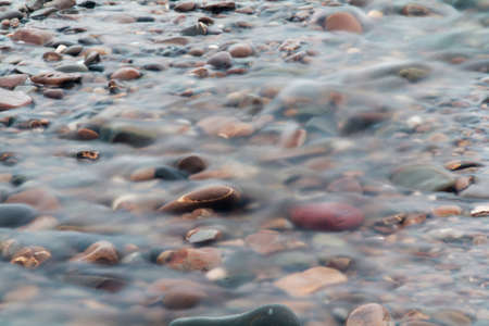 Waves over pebbles on beach. Long exposure.