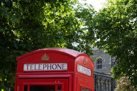 Red telephone box against a background of trees