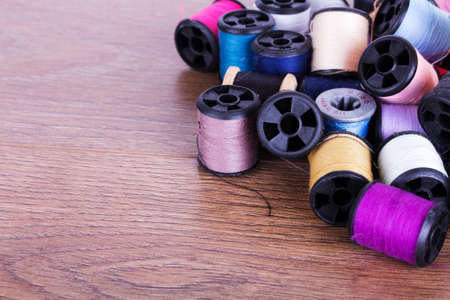 Scattered coloured cotton reels on a wooden surface