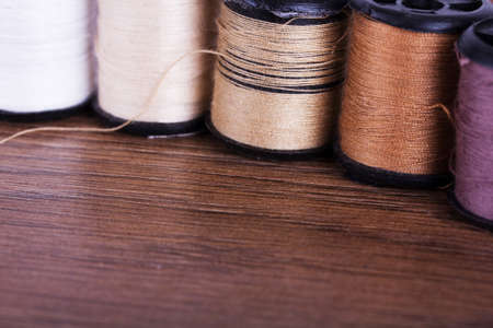 Cotton reels in shades of brown on a wooden surface