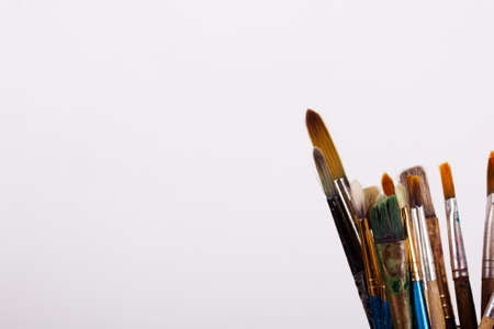 Paint brushes in a glass pot against a white background