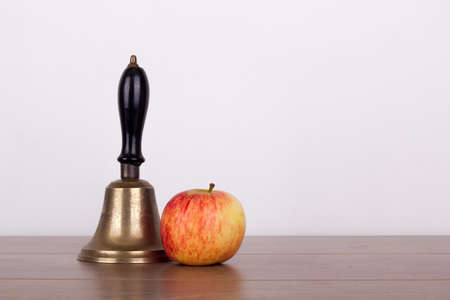 Old fashioned bell and an apple on a wooden surfaceの写真素材