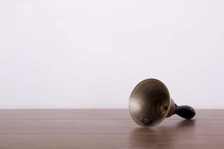 Old fashioned hand bell on a wooden surfaceの写真素材