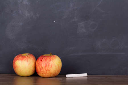 Apple on a wooden surface against an old blackboardの写真素材