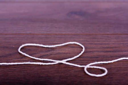 Strand of white string on a rustic wooden surfaceの写真素材