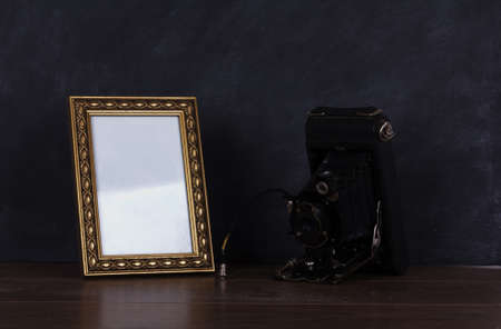 Old vintage camera and frame against blackboard background
