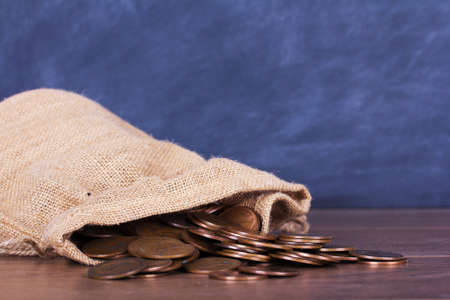 Bag of old coins spilt over a wooden surfaceの写真素材