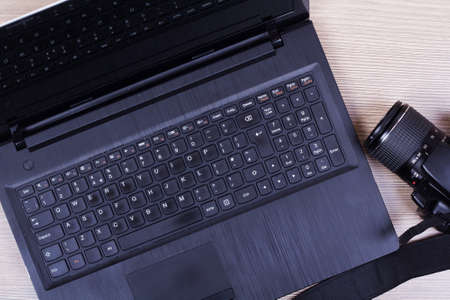 Lay flat image of a laptop and camera on a wooden surface