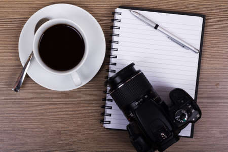 Cup of black coffee and camera on a wooden surfaceの写真素材