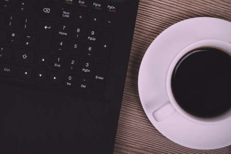 Lay flat image of a laptop and coffee cup on a wooden surface Vintage Retro Filter.の写真素材