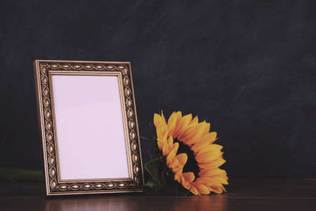 Old picture frame and sunflower against a dirty blackboard background Vintage Retro Filter.の写真素材