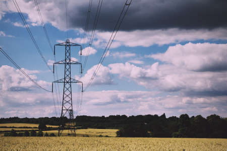 Electricity pylons going across fields in the English countryside Vintage Retro Filter.の写真素材
