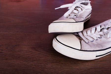 Old worn canvas shoes on a wooden floor