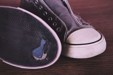 Old worn canvas shoes on a wooden floor Vintage Retro Filter.