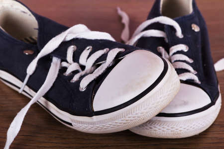Old worn canvas shoes on a wooden floorの写真素材