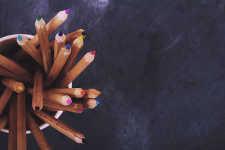 Close up of coloured pencils on a worn black background Vintage Retro Filter.の写真素材