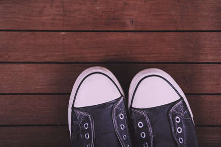 Old worn canvas shoes on a wooden floor Vintage Retro Filter.の写真素材