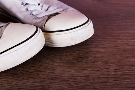 Old worn canvas shoes on a wooden floorの写真素材