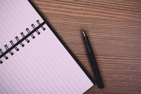 Lay flat image of an open notebook on a wooden surface Vintage Retro Filter.