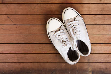 Old worn canvas shoes on a wooden floorの写真素材