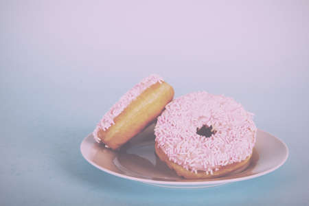 Iced doughnut on a light coloured blue background Vintage Retro Filter.の写真素材